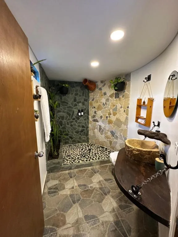 Baño en piedra de una cabaña en Hotel Onsen: ducha tipo cascada y lavamanos en madera