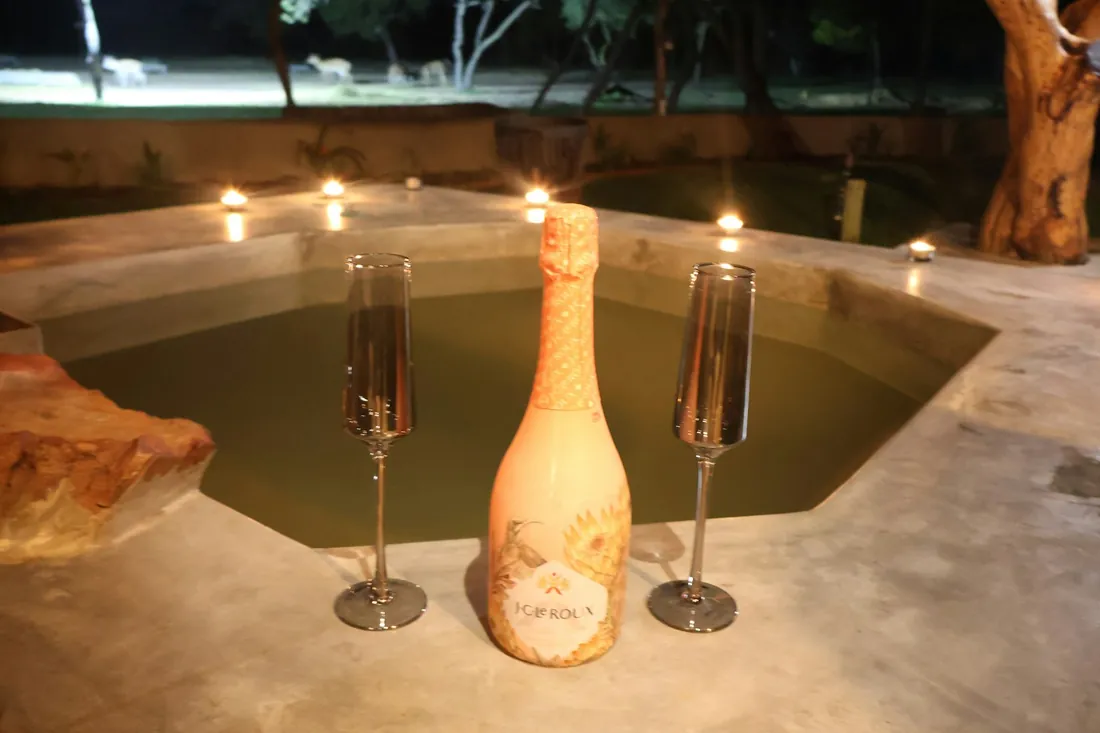 Copas de champaña junto a una tina iluminada con velas, ambiente romántico
